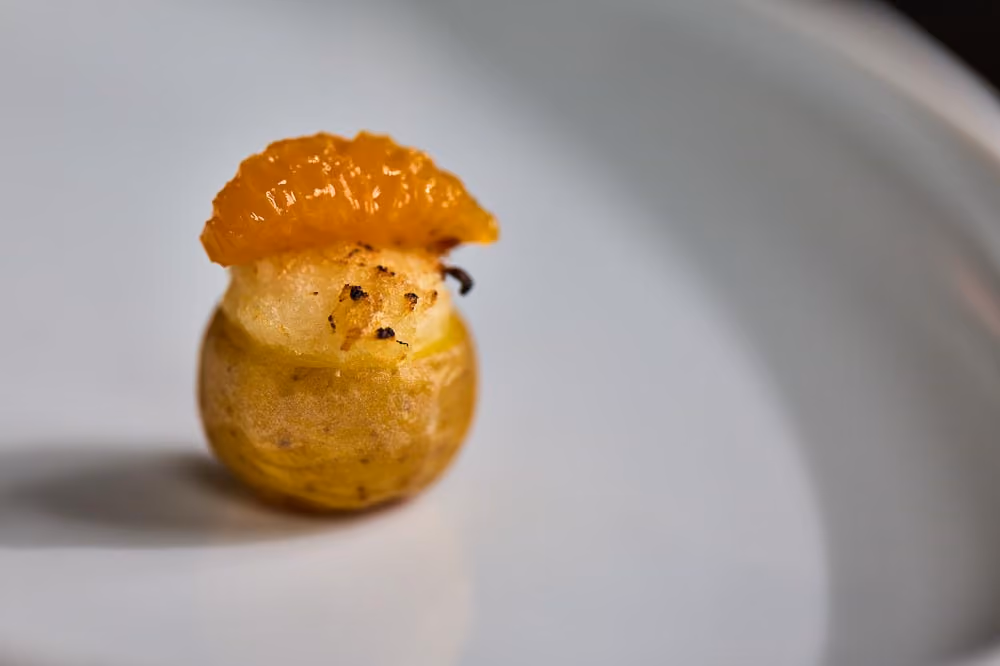 Roasted baby potato bite topped with candied orange