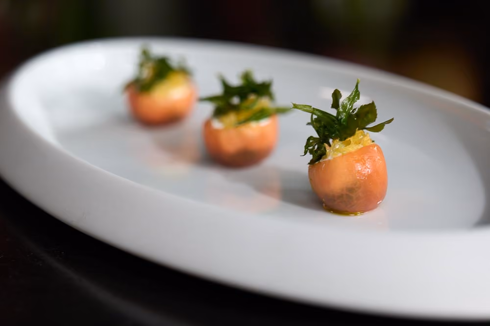 Three cherry tomato canapés topped with herb salad