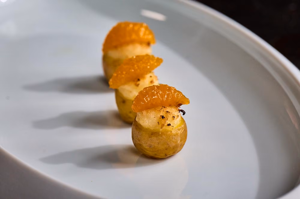 Three roasted baby potato bites topped with candied orange segments