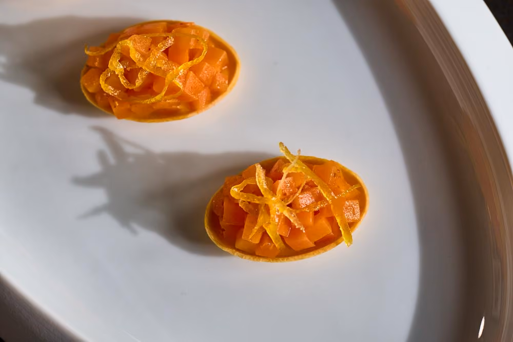 Two oval tartlets topped with diced papaya and candied citrus zest