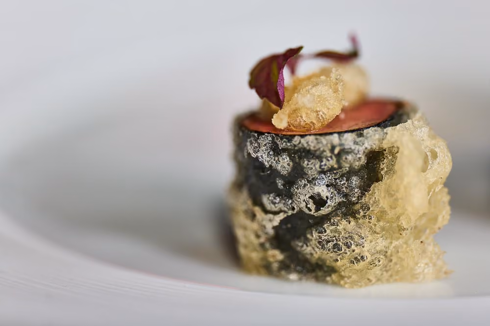 Nori-wrapped rice canapé topped with crispy tempura bits and a purple leaf
