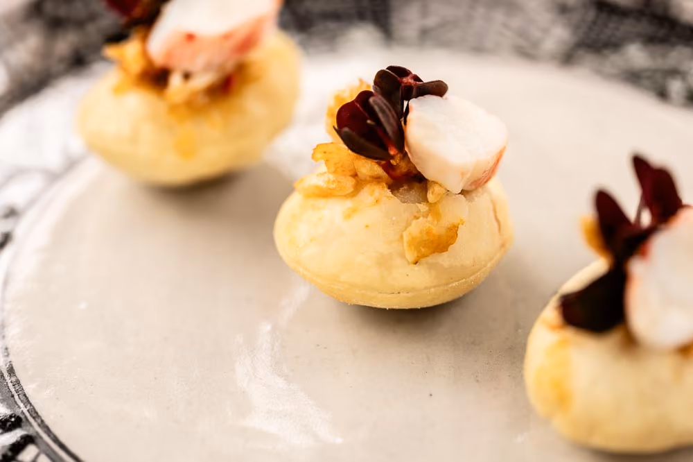 Three choux pastry canapés topped with scallop and microgreens