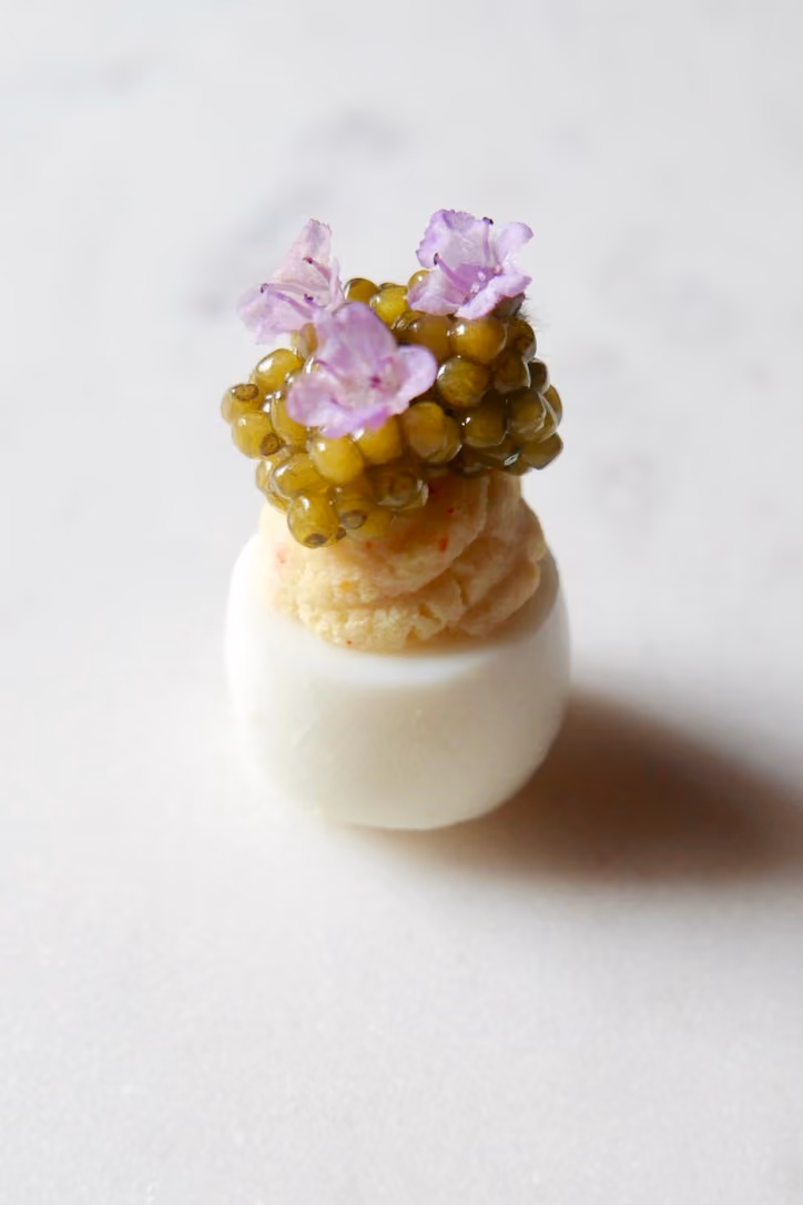 Deviled quail egg topped with caviar and purple flowers