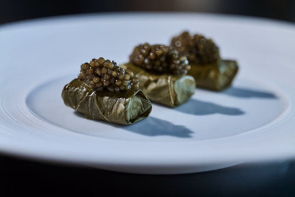 Three grape leaf dolmas topped with caviar