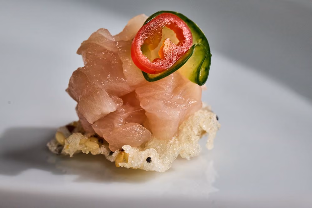 Diced yellowtail canapé on a crispy rice cracker topped with jalapeño and avocado