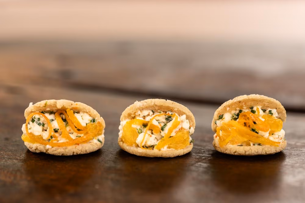 Row of sandwich cookies filled with whipped cheese and crispy citrus zest