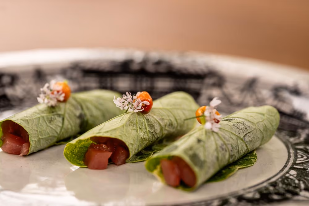 Three collard-wrapped tuna tartare rolls garnished with white flowers