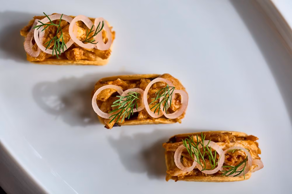 Three tartlets topped with curried chicken salad and pickled shallot rings, garnished with dill