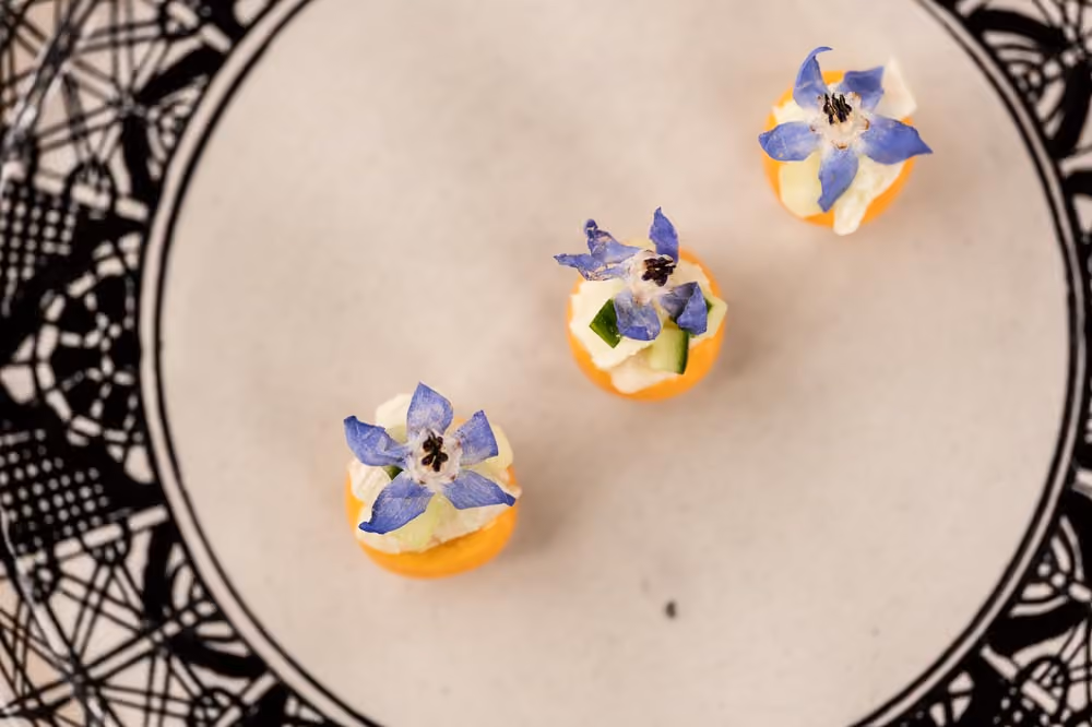 Three canapés topped with diced cucumber and blue borage flowers