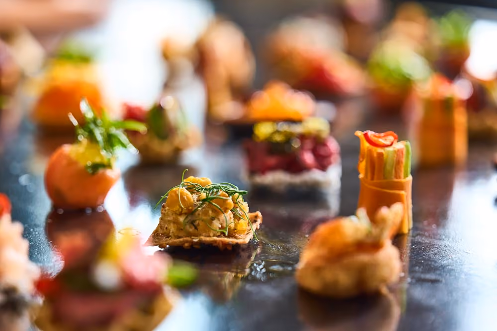 Overhead close-up of assorted bite-sized canapés arranged on a dark table