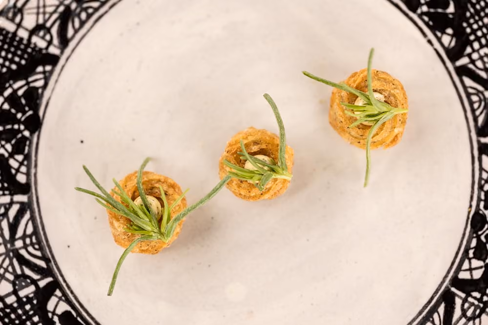 Three crispy pastry nests topped with roasted garlic and a rosemary sprig