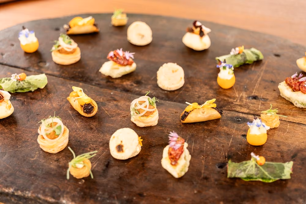 Overhead assortment of bite-sized canapés arranged on a round wooden board