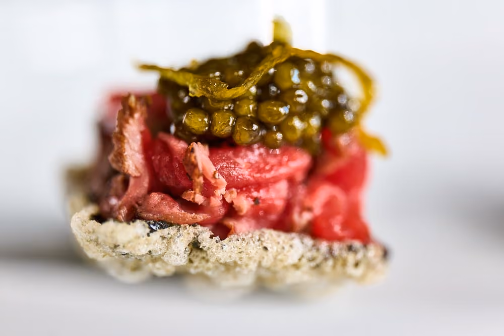 Crispy tuile canapé topped with sliced beef tartare and caviar