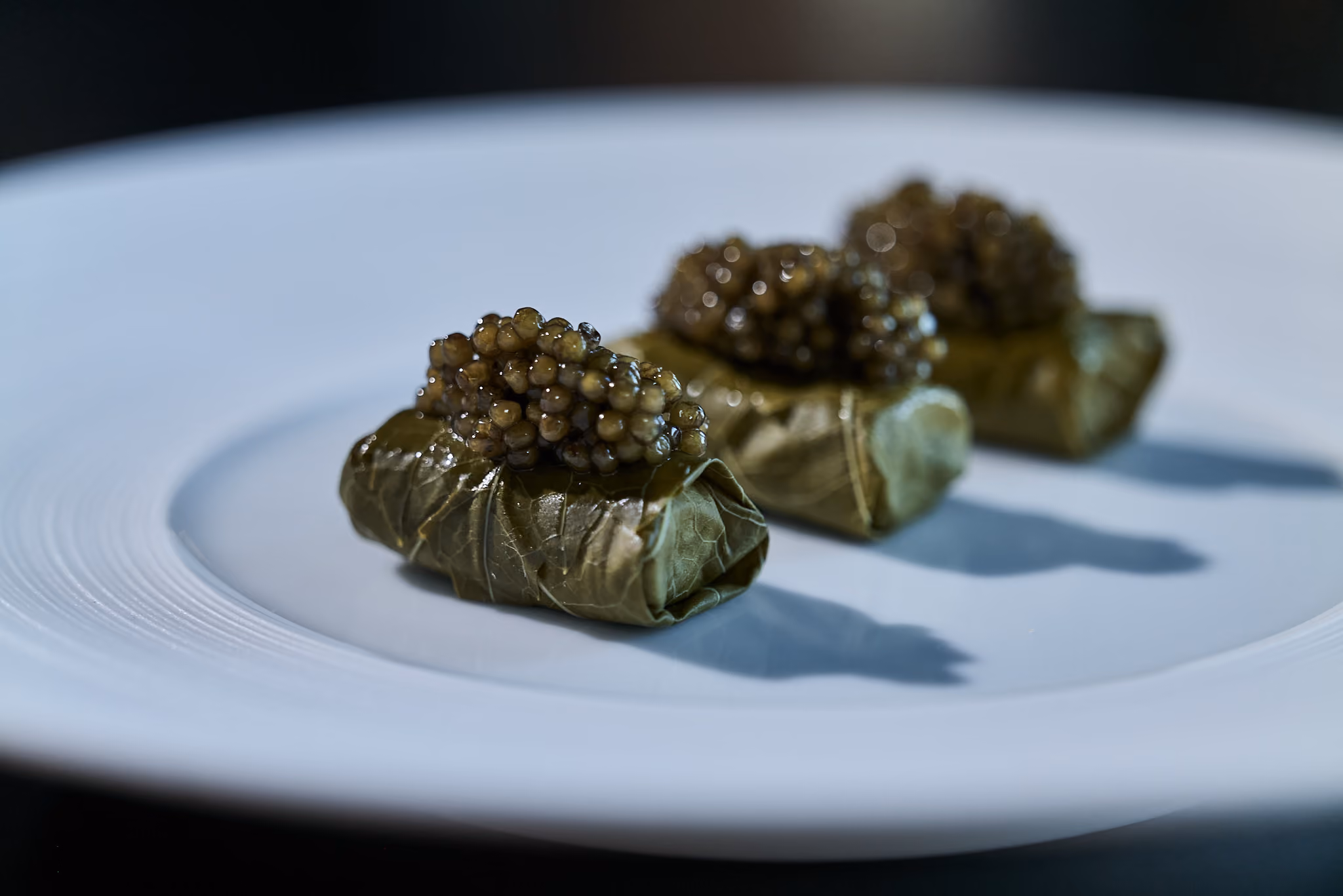 Three grape-leaf-wrapped canapés topped with caviar