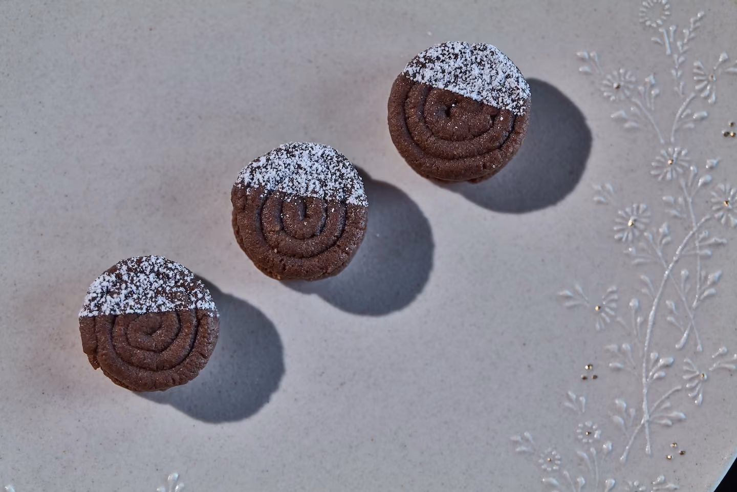 Row of chocolate pinwheel cookies dusted with powdered sugar