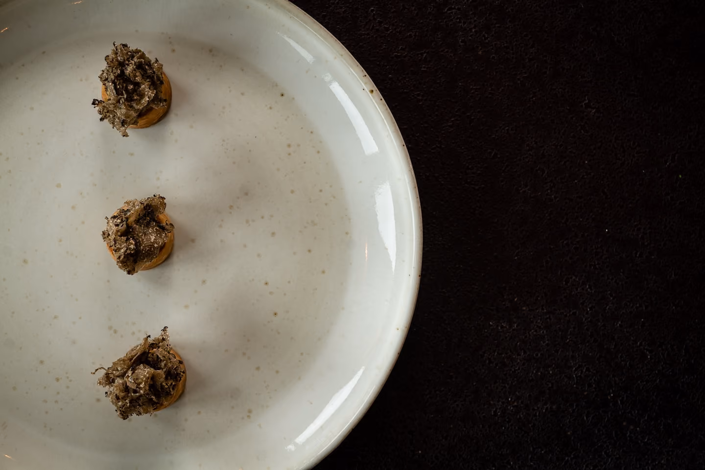 Overhead row of crostini topped with crispy fried herbs