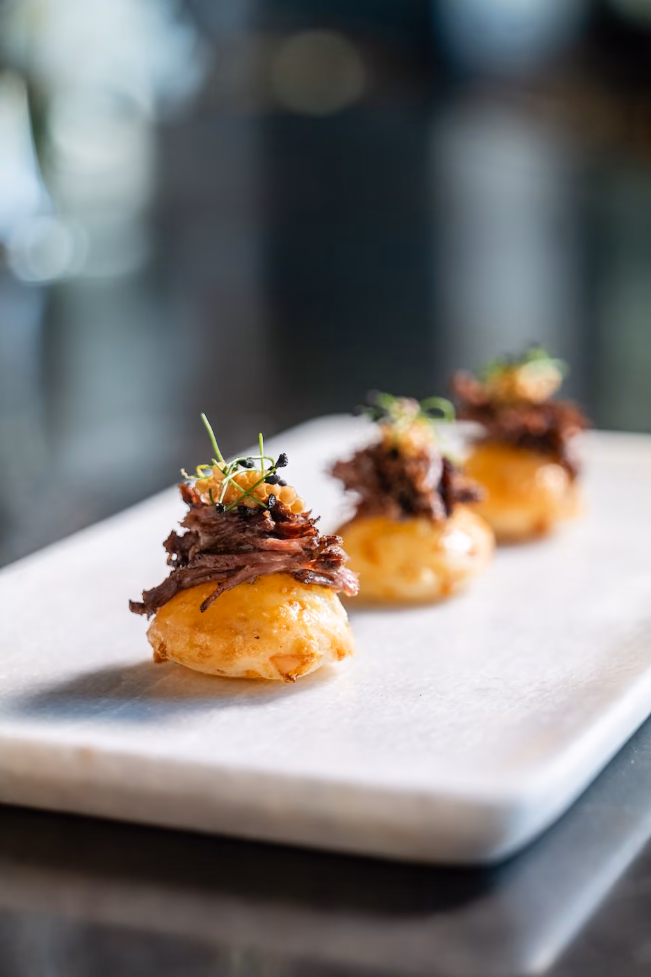 Row of gougère canapés topped with braised short rib