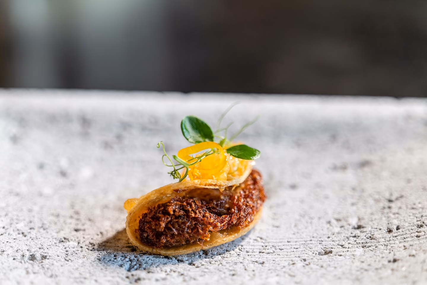 Crispy tuile canapé filled with braised short rib and topped with pea shoots