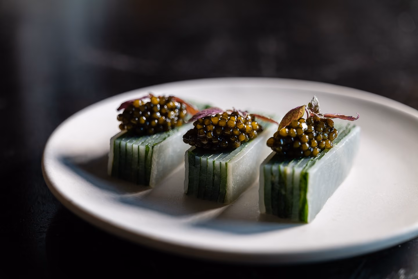 Row of jicama batons topped with caviar and pink shiso