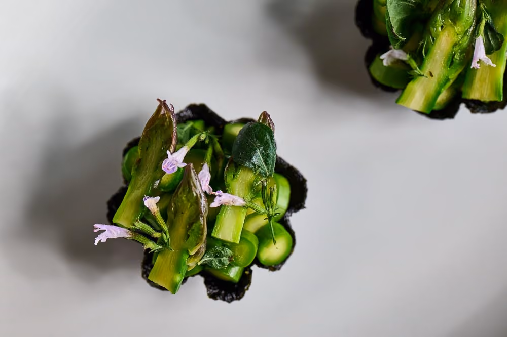 Black tart shell filled with asparagus, sage, and purple flowers