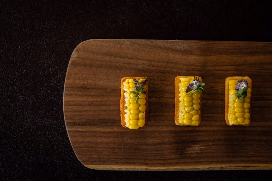 Row of corn-topped tartlets garnished with edible flowers