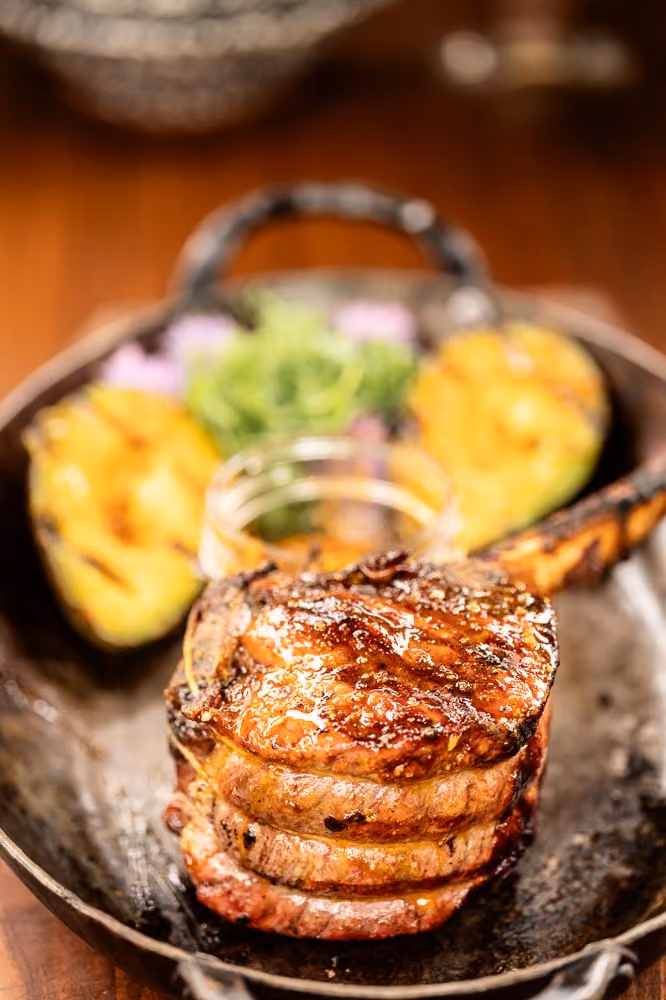 Stacked grilled pork chops with grilled avocado halves in a cast iron pan