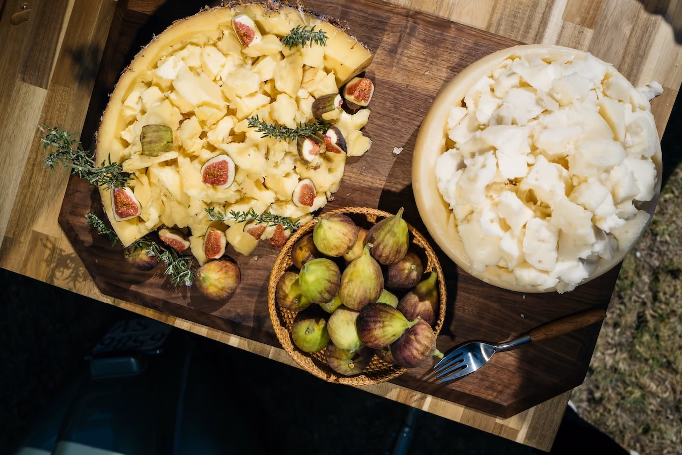 Overhead wooden board with an assortment of cheeses and fresh figs