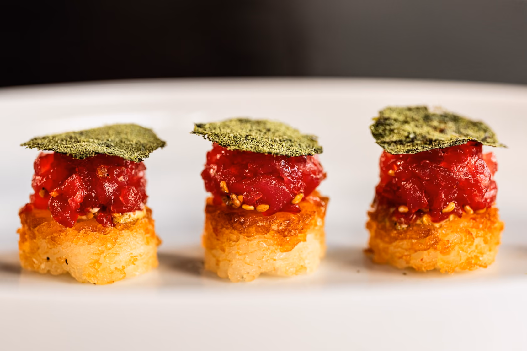 Tuna tartare canapés on crispy rice cakes topped with a nori crisp