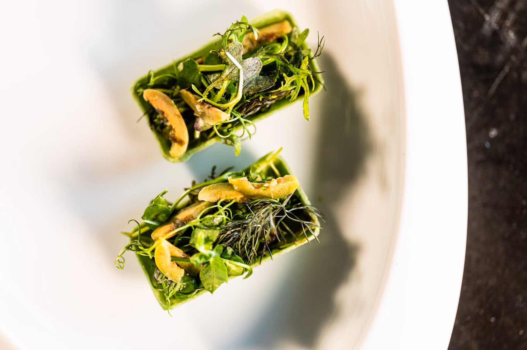 Overhead pair of green tartlet boats topped with mushrooms and microgreens