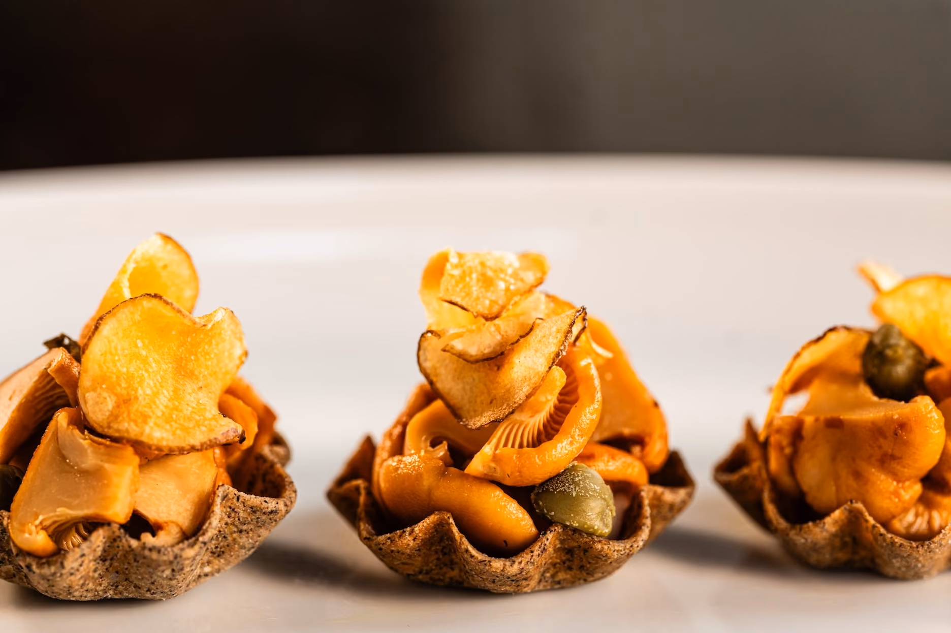 Tart shells filled with wild mushrooms and topped with crispy potato chips