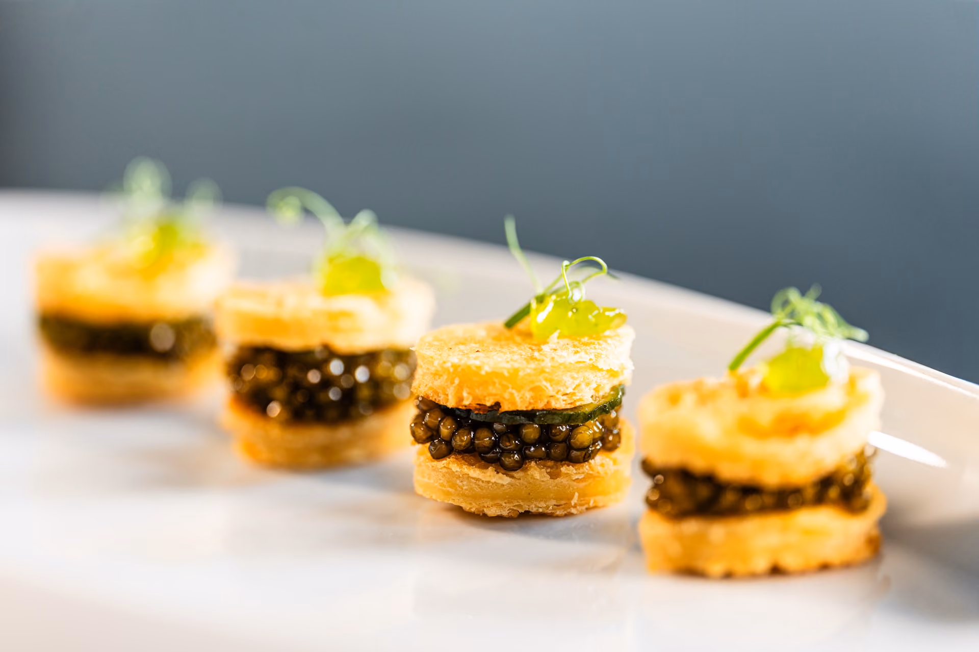 Row of puff pastry canapés layered with caviar and a citrus gel garnish