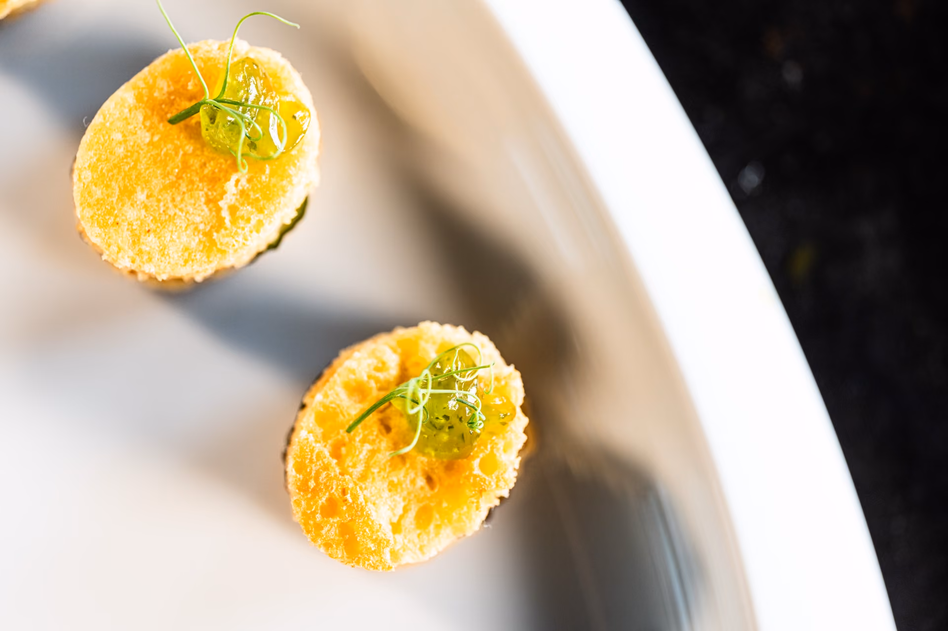 Overhead view of two tempura-battered canapés topped with a green pickled garnish