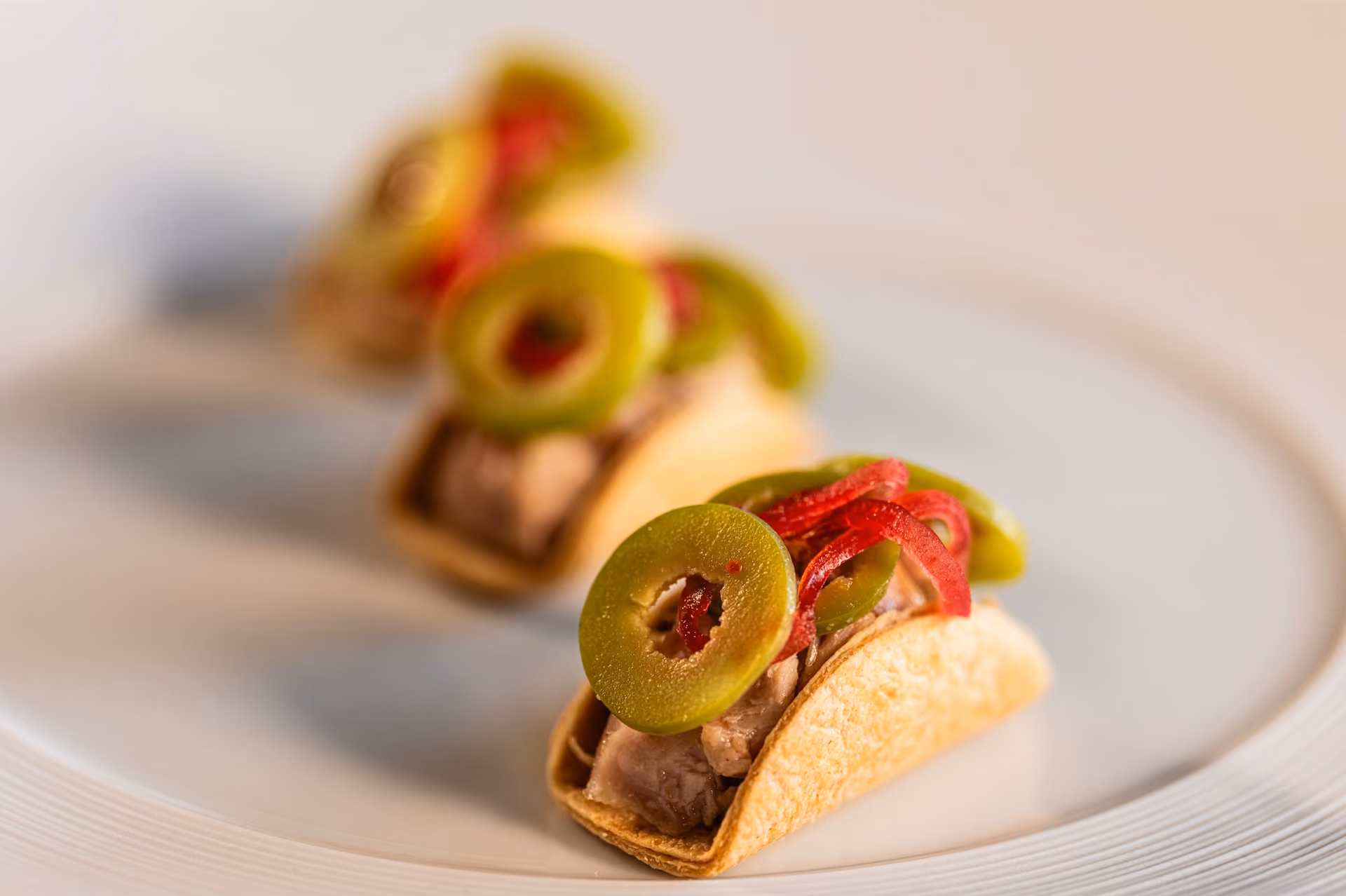 Taco-shaped canapés topped with olive slices and red pepper strips