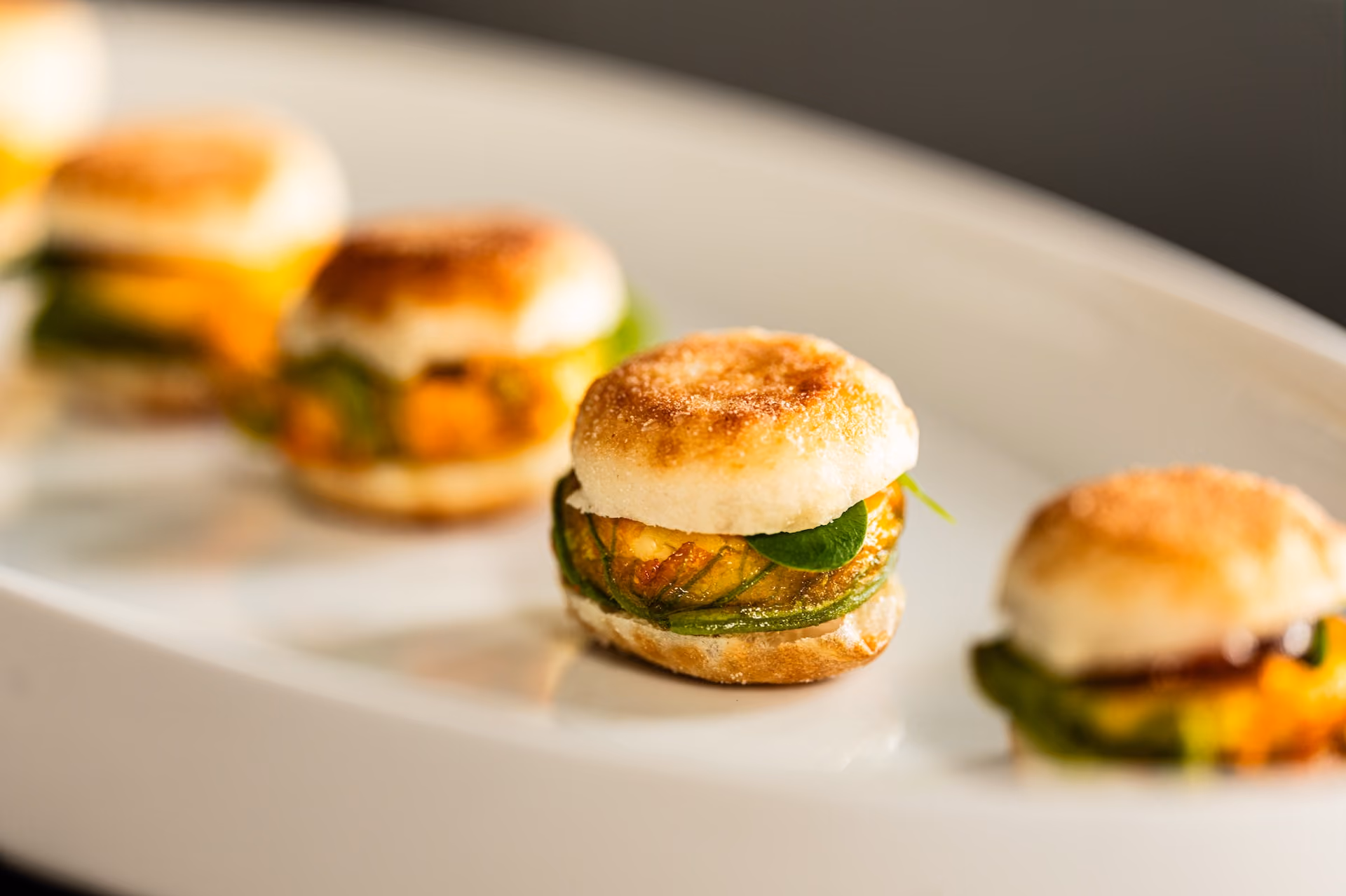 Mini English muffin sliders with a savory filling and fresh greens