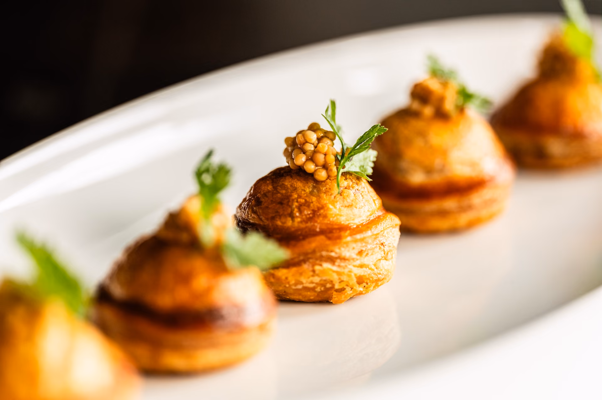 Vol-au-vent pastry puffs topped with mustard seed caviar and herb garnish