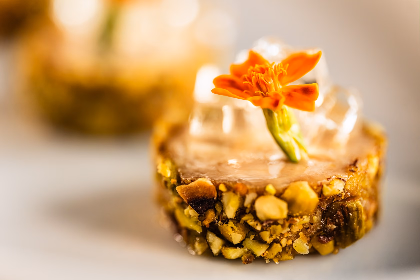 Pistachio-crusted canapé topped with an edible marigold flower and a clear gel garnish
