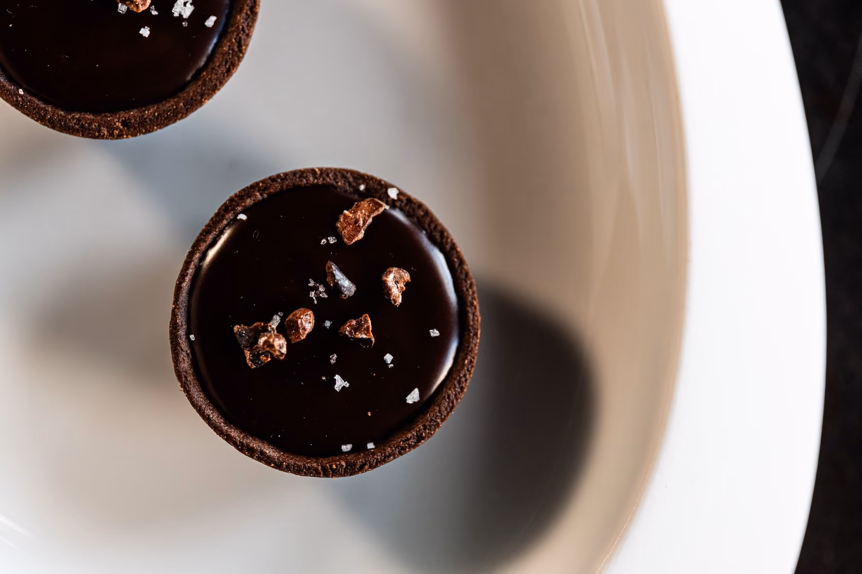 Overhead view of a chocolate tartlet topped with cacao nibs and sea salt