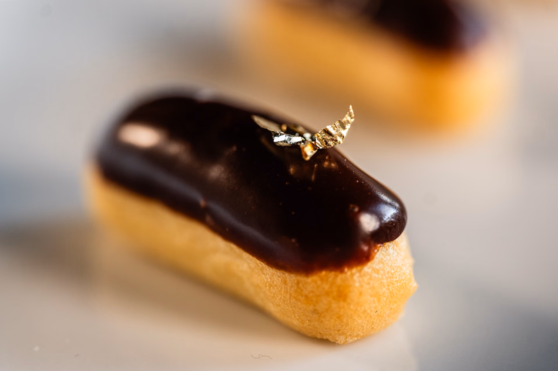 Chocolate-glazed eclair garnished with a flake of gold leaf