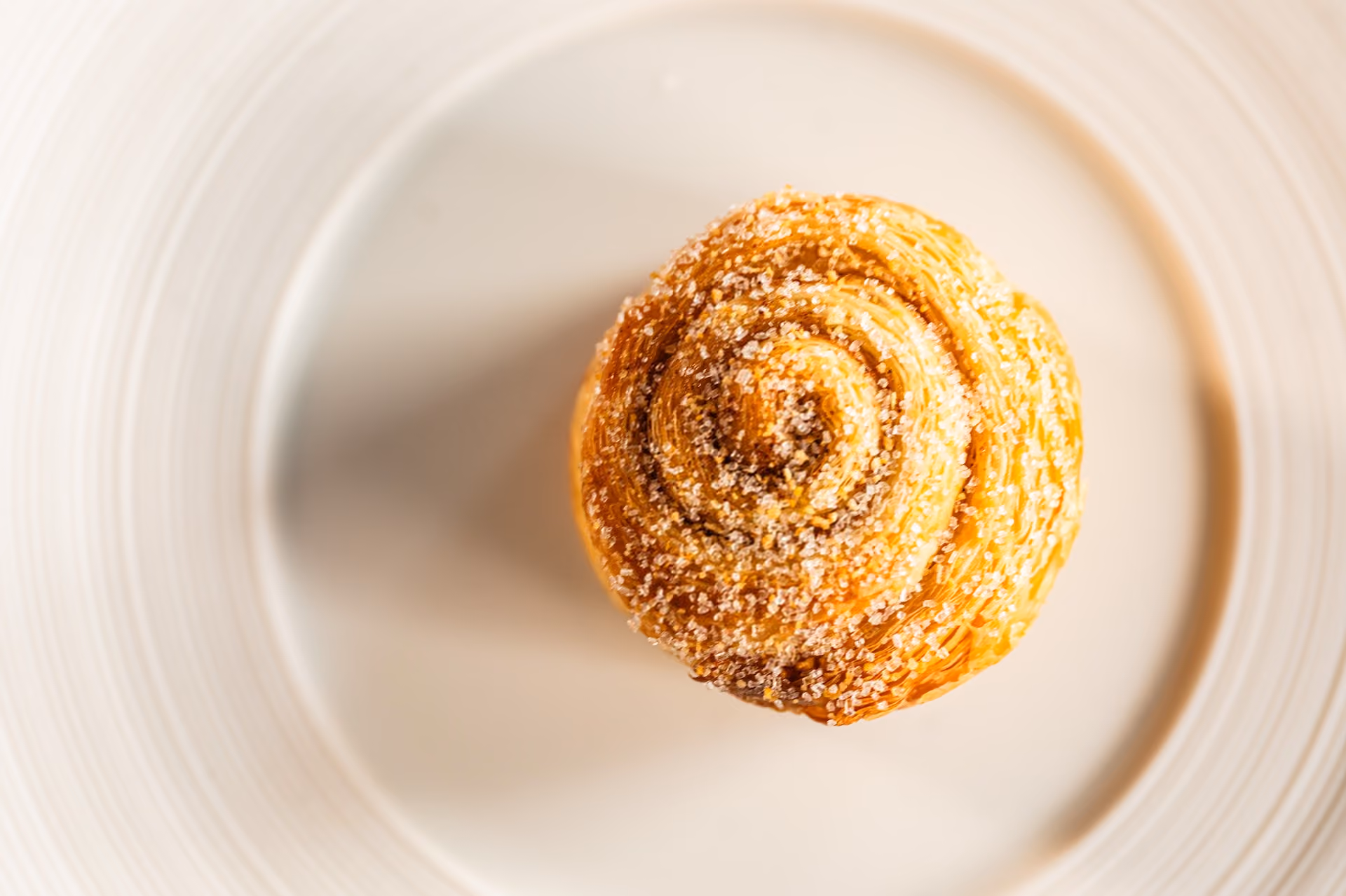 Overhead view of a spiral kouign-amann pastry finished with sugar crystals