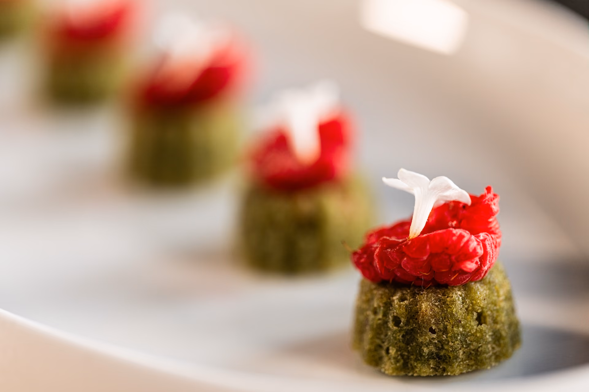 Matcha tea cakes topped with raspberry compote and a white flower garnish