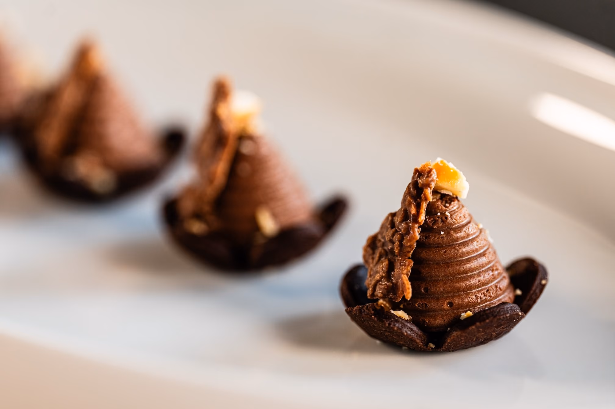 Chocolate mousse dessert cones topped with crispy praline and gold leaf