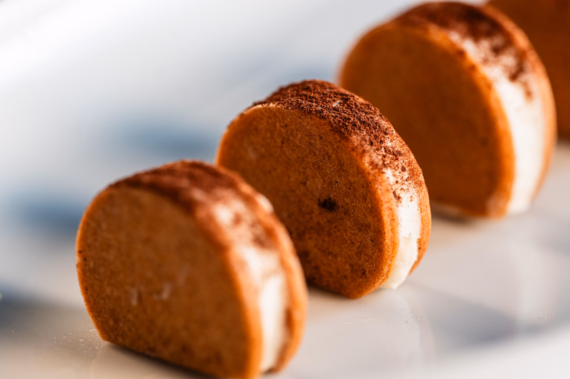 Sliced tiramisu-style roll cakes dusted with cocoa powder, showing a cream filling