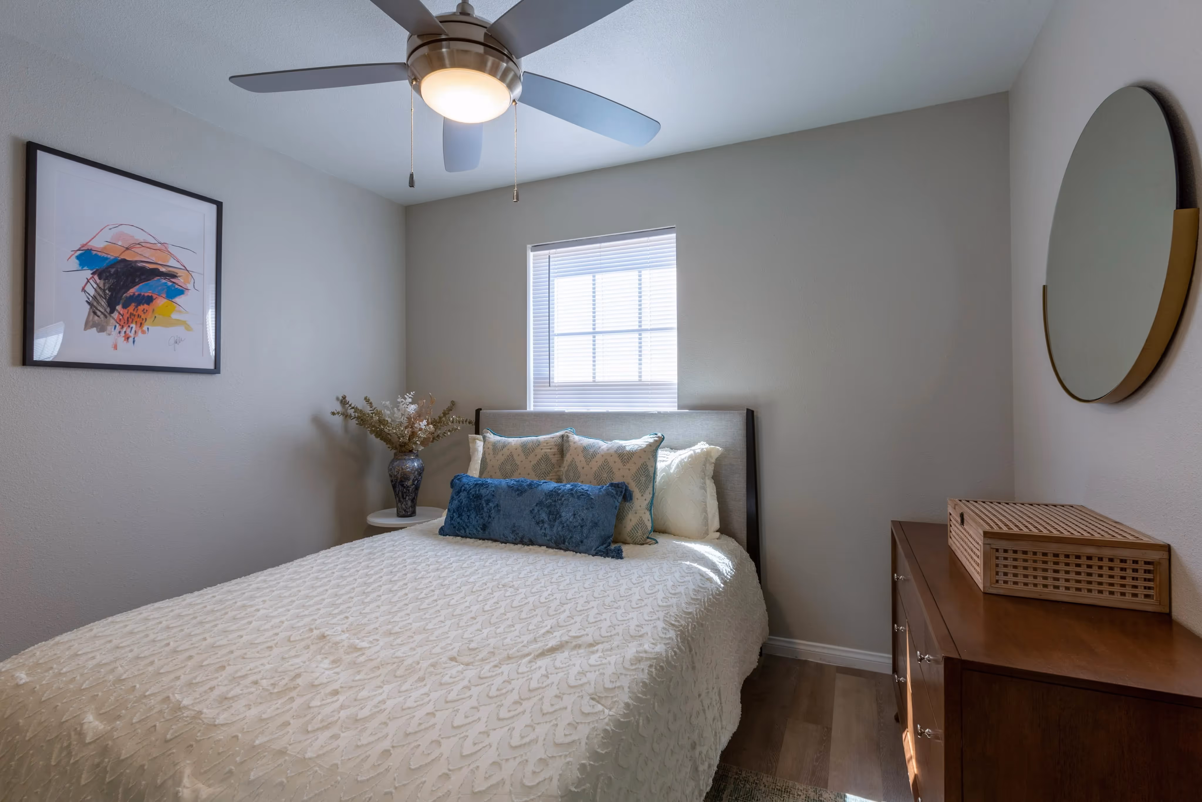 Bright bedroom with a modern bed, ceiling fan, and hardwood-style floors, in an apartment at Ascension at Ironwood in Tucson, AZ.