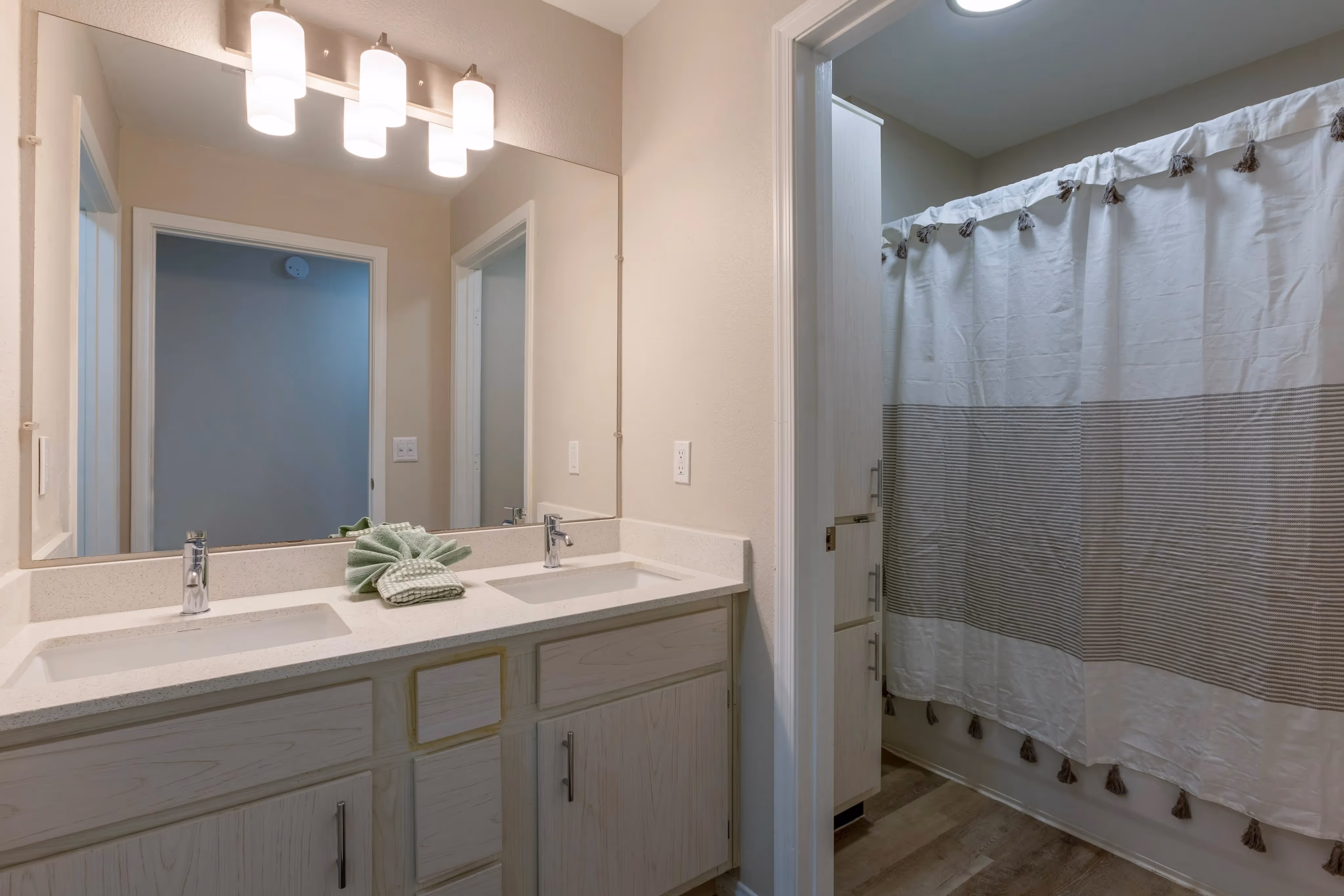 Spacious bathroom with a double vanity, large mirror, and a walk-in shower/tub combination, in an apartment at Ascension at Ironwood in Tucson, AZ.