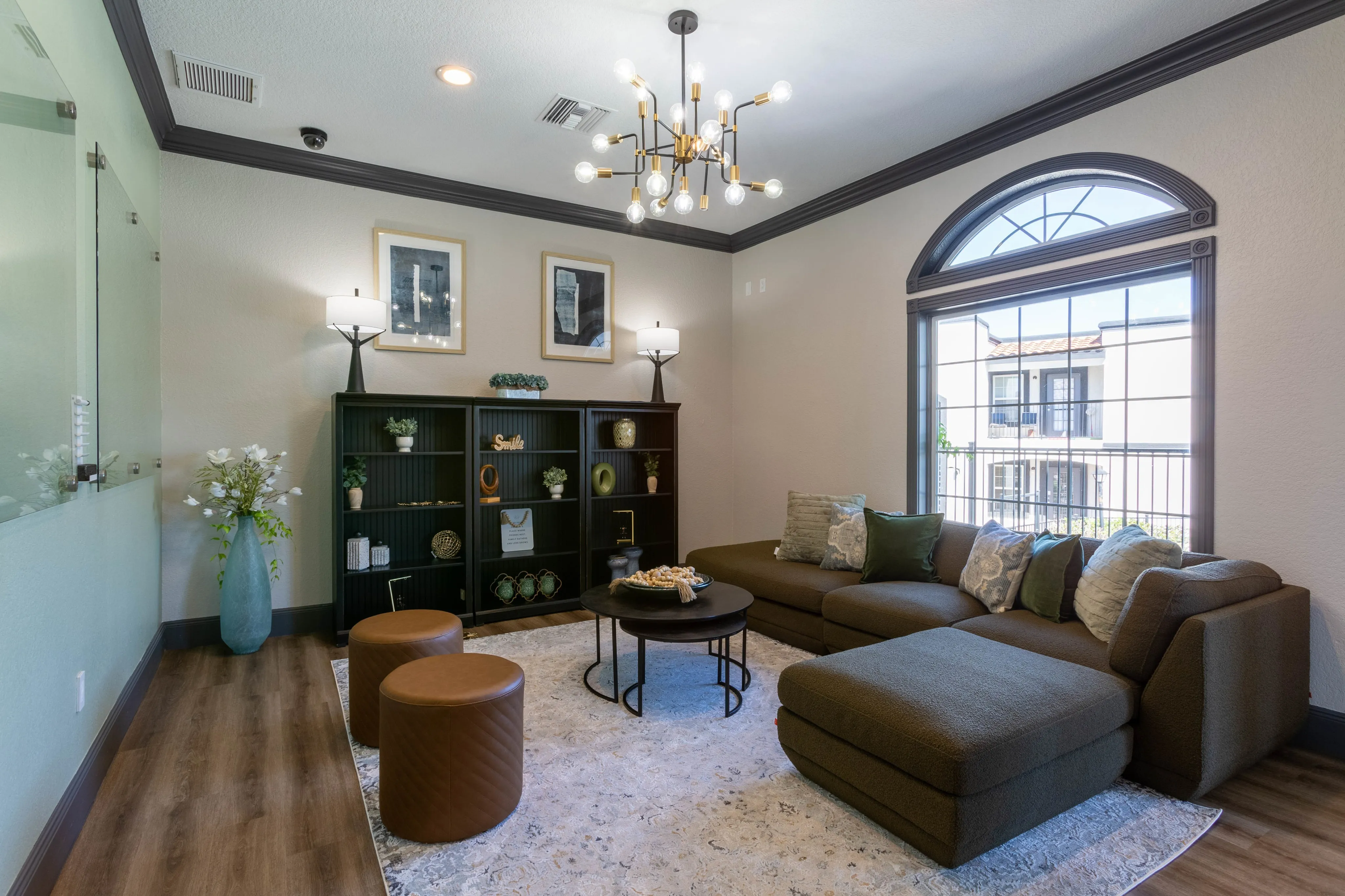 Elegant clubhouse lounge with a sectional sofa, unique chandelier, and large windows, a welcoming space at Ascension at Ironwood in Tucson, AZ.