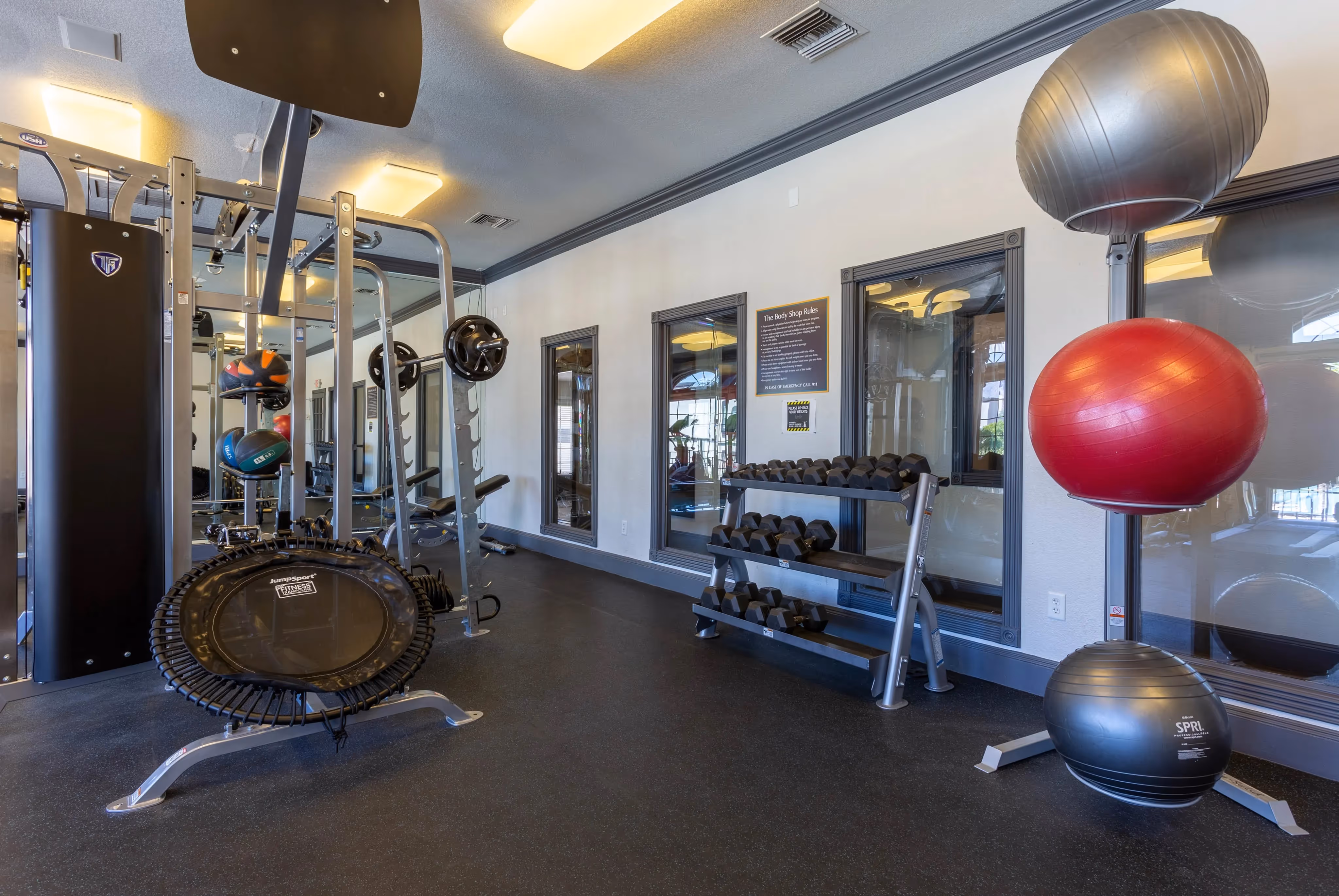 Comprehensive gym with free weights, various machines, and a trampoline, offering a well-equipped workout space at Ascension at Ironwood in Tucson, AZ.