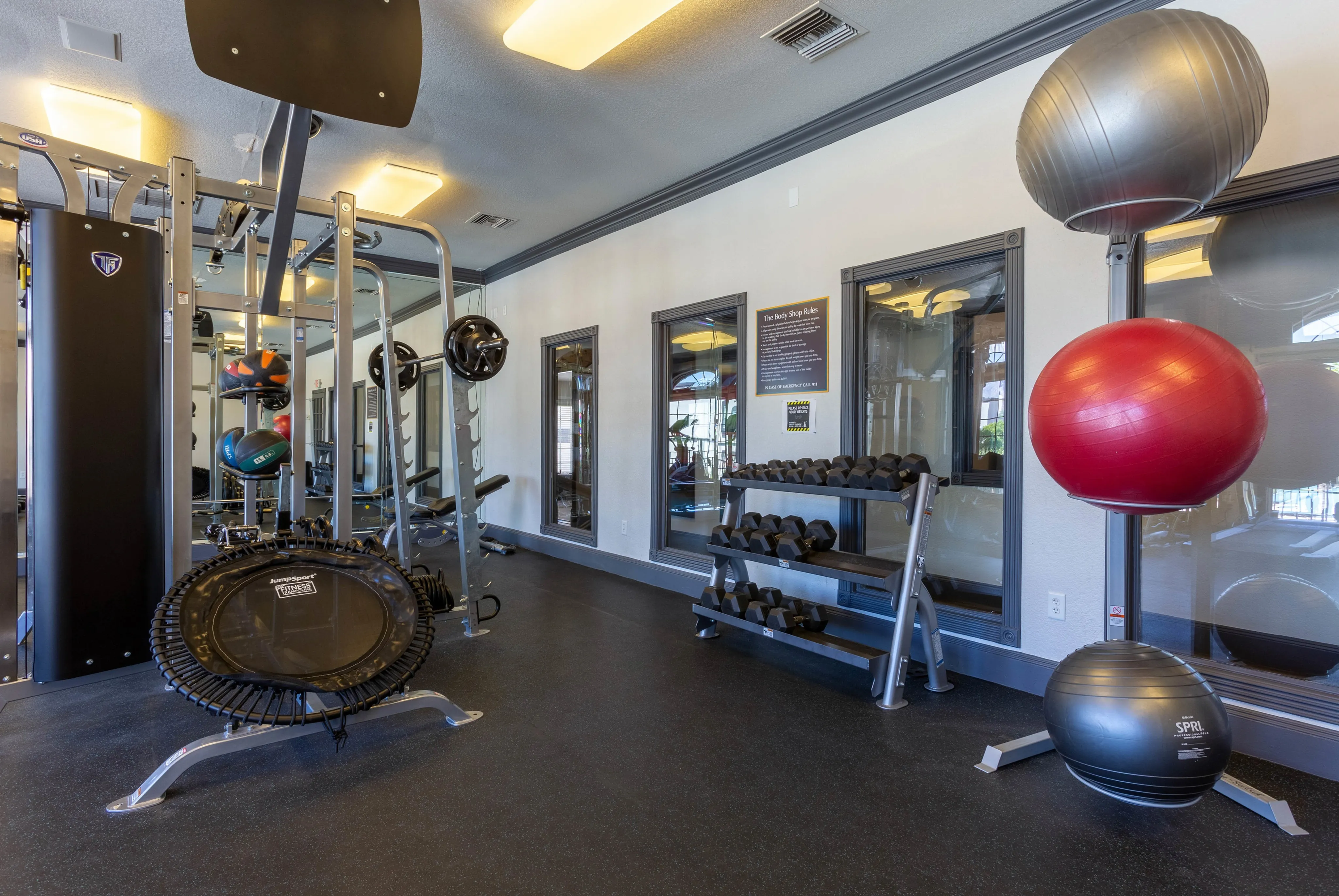 Comprehensive gym with free weights, various machines, and a trampoline, offering a well-equipped workout space at Ascension at Ironwood in Tucson, AZ.