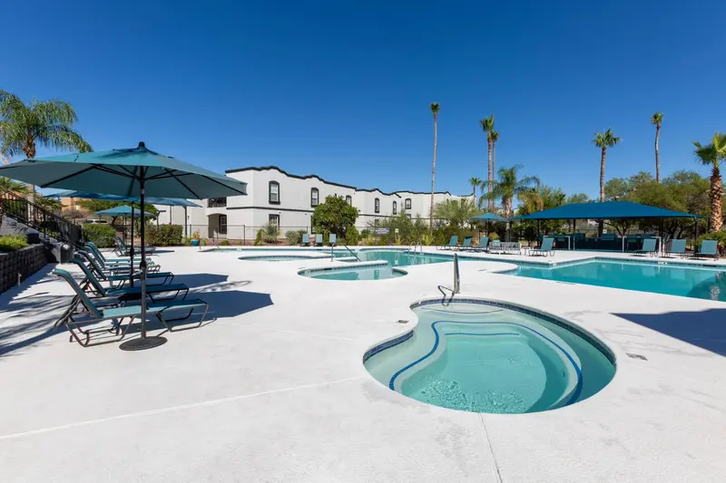 Resort-style swimming pool and hot tub area with a spacious sundeck and palm trees, a key amenity at Ascension at Ironwood in Tucson, AZ.