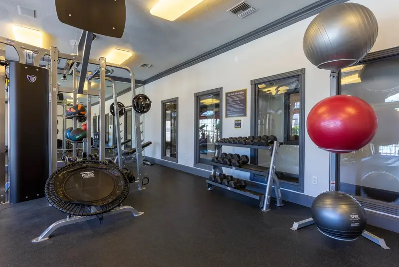 Comprehensive gym with free weights, various machines, and a trampoline, offering a well-equipped workout space at Ascension at Ironwood in Tucson, AZ.