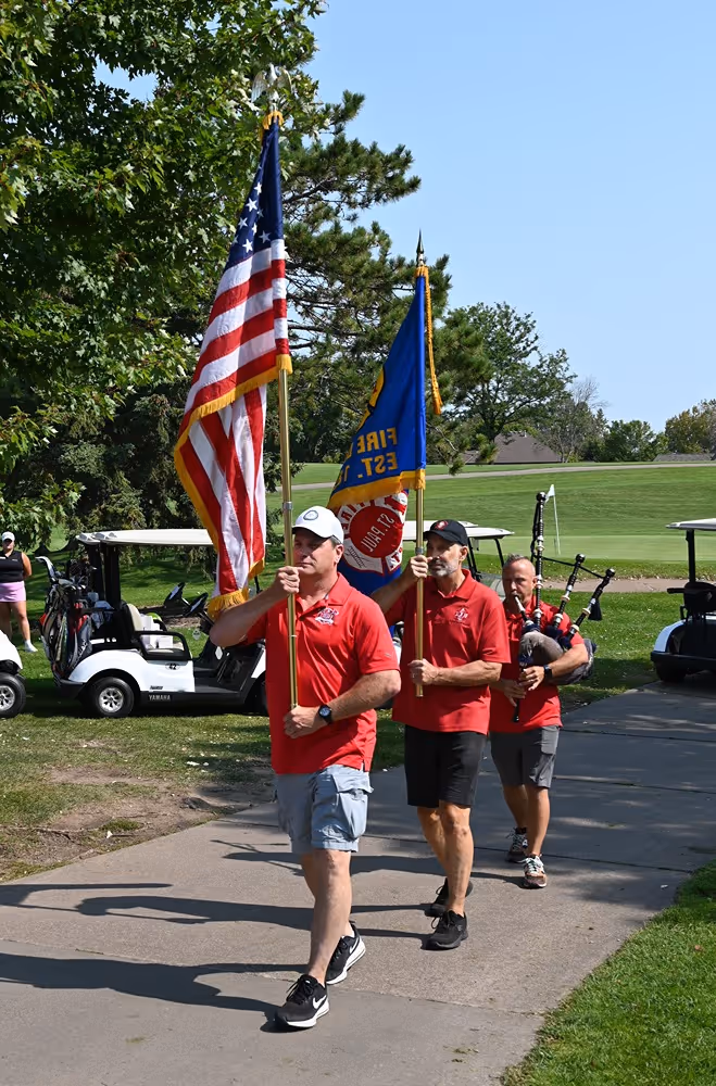 Saint Paul Firefighters Local 21 members carrying the American flag and union flag during a golf event.